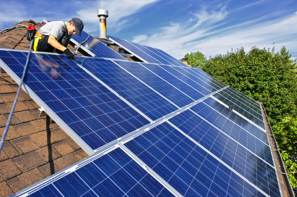 Homme installant des panneaux photovoltaïques sur un toit de maison